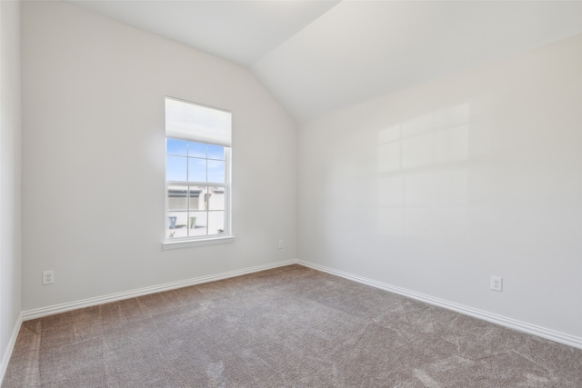 carpeted spare room featuring vaulted ceiling