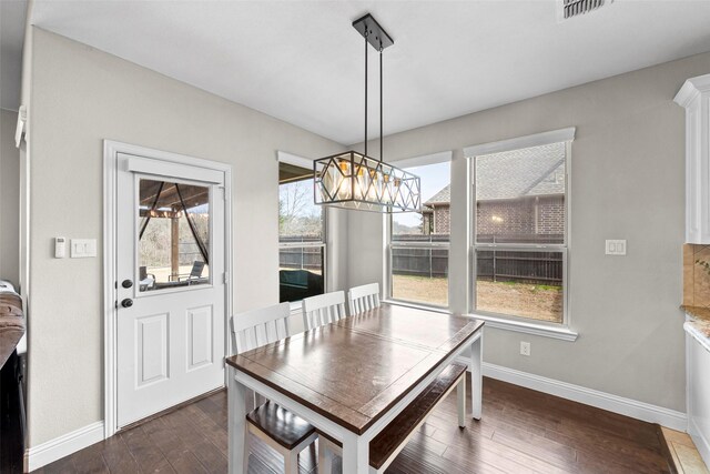 dining space with ceiling fan, a stone fireplace, and dark hardwood / wood-style flooring