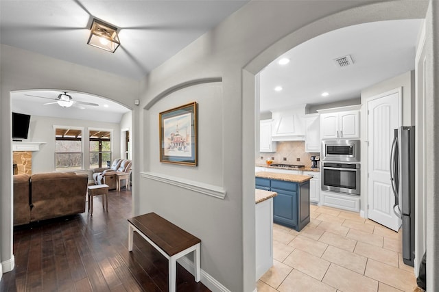 kitchen with backsplash, a kitchen island, stainless steel appliances, white cabinets, and blue cabinets