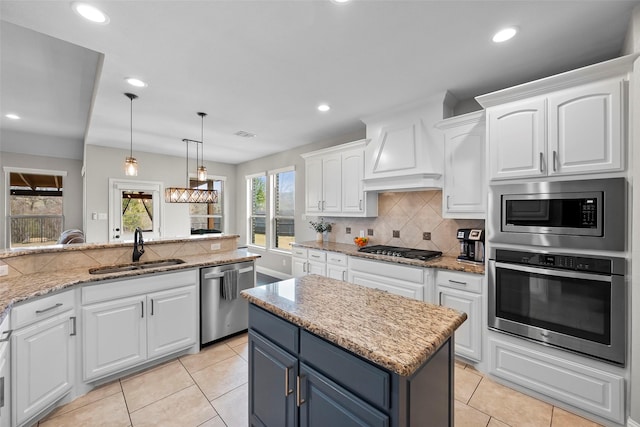 kitchen featuring sink, white cabinetry, a kitchen island, stainless steel appliances, and light stone countertops