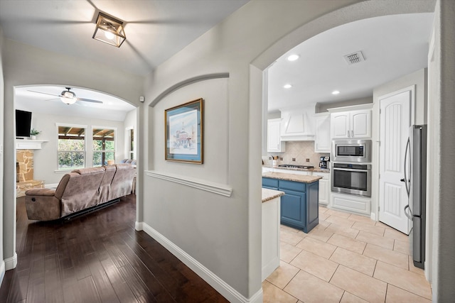 kitchen with blue cabinets, white cabinets, custom exhaust hood, a center island, and stainless steel appliances