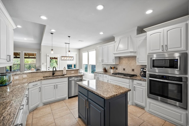 kitchen with white cabinetry, appliances with stainless steel finishes, sink, and a center island