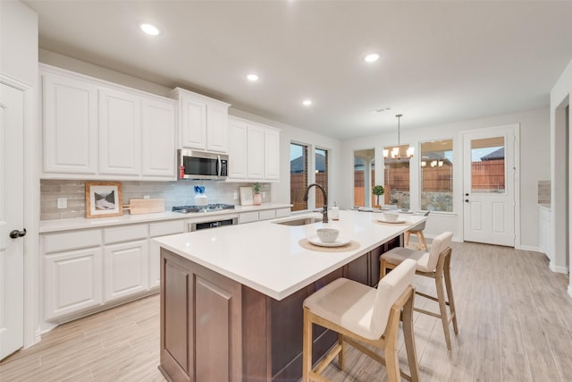 kitchen featuring a sink, stainless steel appliances, light countertops, white cabinets, and backsplash