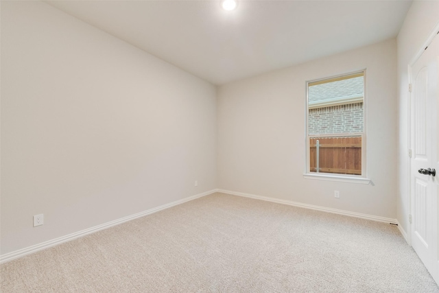 unfurnished room featuring light carpet and baseboards