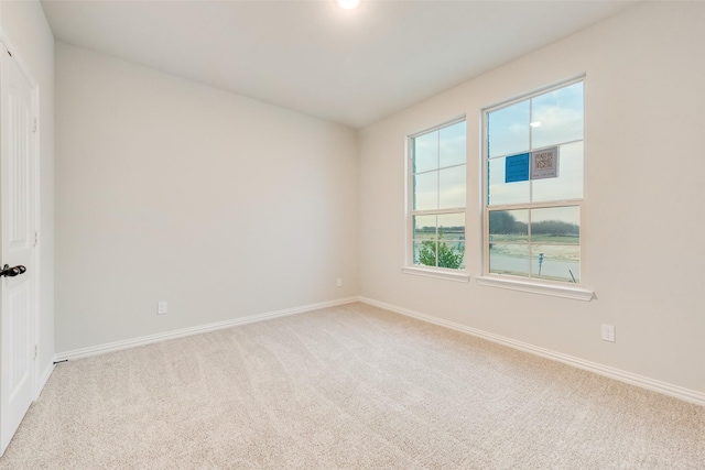 unfurnished room featuring baseboards and light carpet