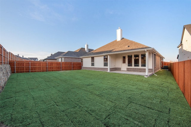 rear view of property featuring a patio area, a fenced backyard, a lawn, and brick siding