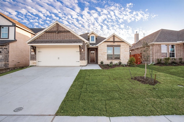 view of front of home with an attached garage, a shingled roof, concrete driveway, a front lawn, and stone siding