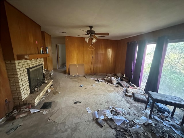 miscellaneous room with a fireplace, ceiling fan, and wooden walls