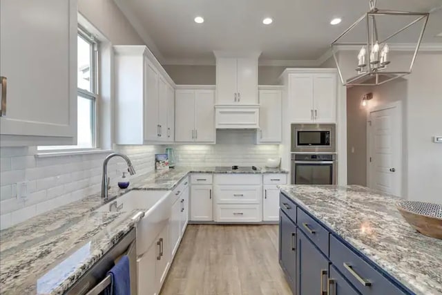 kitchen with white cabinets, ornamental molding, blue cabinetry, and appliances with stainless steel finishes