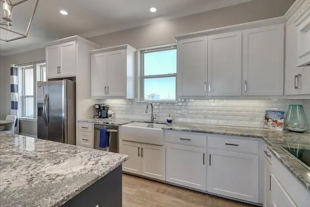 kitchen featuring decorative backsplash, white cabinetry, stainless steel appliances, and light wood-type flooring