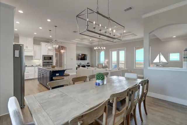 dining area featuring a raised ceiling, light hardwood / wood-style floors, and ornamental molding