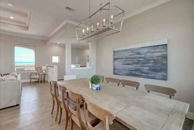 dining area with crown molding, wood-type flooring, and a notable chandelier