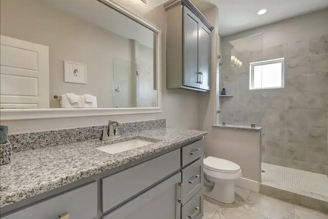 bathroom featuring vanity, toilet, and a tile shower