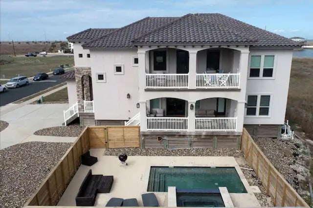 back of property with an in ground hot tub and a balcony