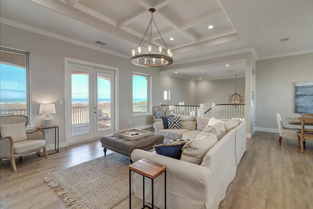 living room featuring a notable chandelier, a water view, light wood-type flooring, and ornamental molding