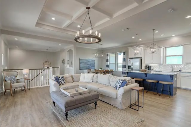 living room featuring beam ceiling, sink, light hardwood / wood-style floors, and coffered ceiling