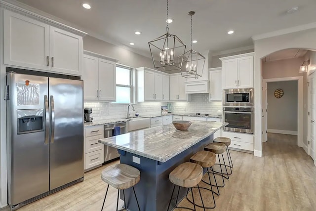 kitchen featuring white cabinets, appliances with stainless steel finishes, a center island, and tasteful backsplash