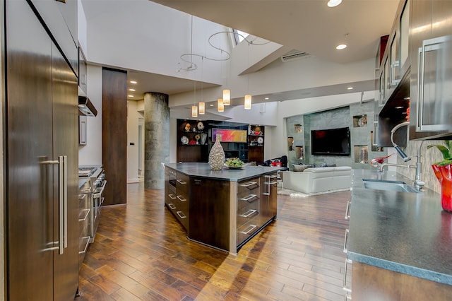 kitchen with dark brown cabinets, high end appliances, dark wood-type flooring, sink, and pendant lighting