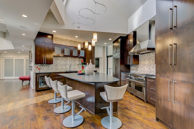 kitchen with dark hardwood / wood-style flooring, a center island, wall chimney exhaust hood, and range with two ovens