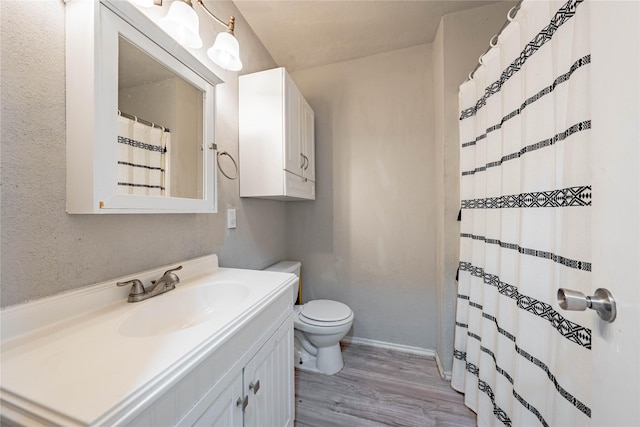 bathroom with toilet, vanity, and hardwood / wood-style flooring