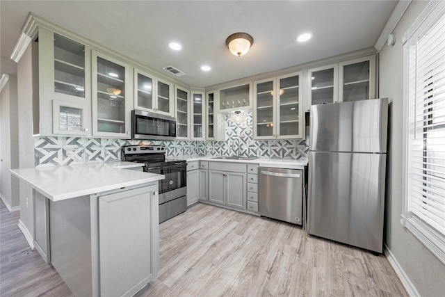 kitchen featuring kitchen peninsula, stainless steel appliances, tasteful backsplash, and crown molding