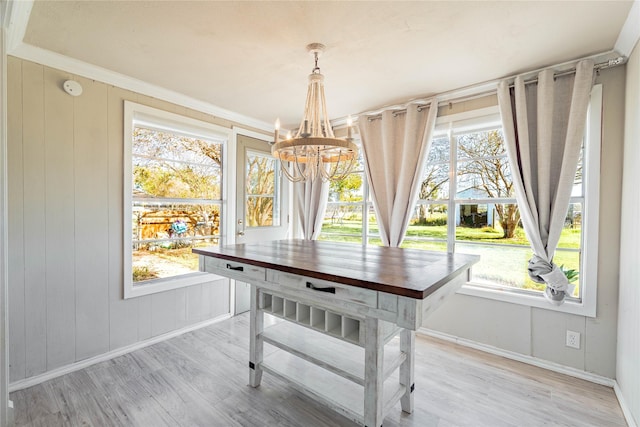 dining space featuring light wood-type flooring, an inviting chandelier, and a healthy amount of sunlight