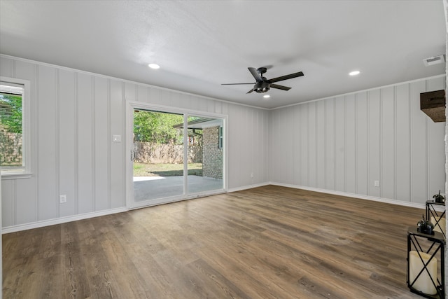 empty room featuring dark hardwood / wood-style floors, a wealth of natural light, ornamental molding, and ceiling fan