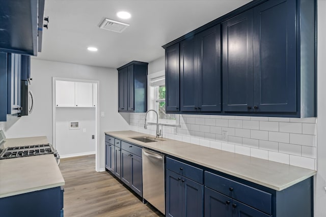 kitchen featuring blue cabinetry, sink, light hardwood / wood-style flooring, decorative backsplash, and appliances with stainless steel finishes