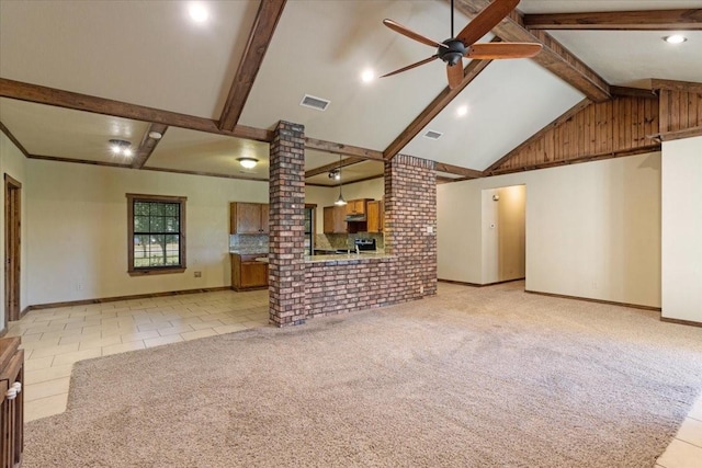 unfurnished living room featuring beam ceiling, light colored carpet, ceiling fan, and ornate columns