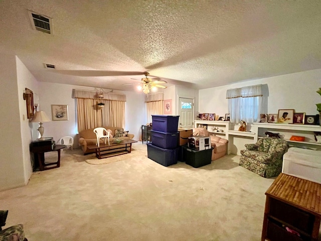 living room featuring ceiling fan, carpet floors, and a textured ceiling