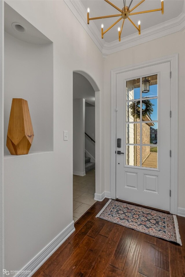 entryway featuring dark hardwood / wood-style flooring, a notable chandelier, and ornamental molding