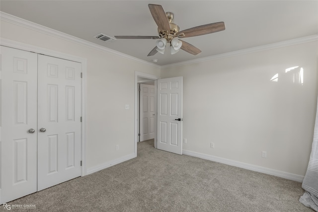 unfurnished bedroom featuring ceiling fan, light colored carpet, ornamental molding, and a closet