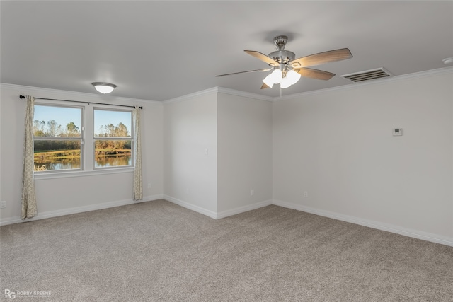 carpeted spare room with ceiling fan, a water view, and crown molding