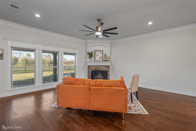 living room with crown molding, ceiling fan, dark hardwood / wood-style floors, and a brick fireplace