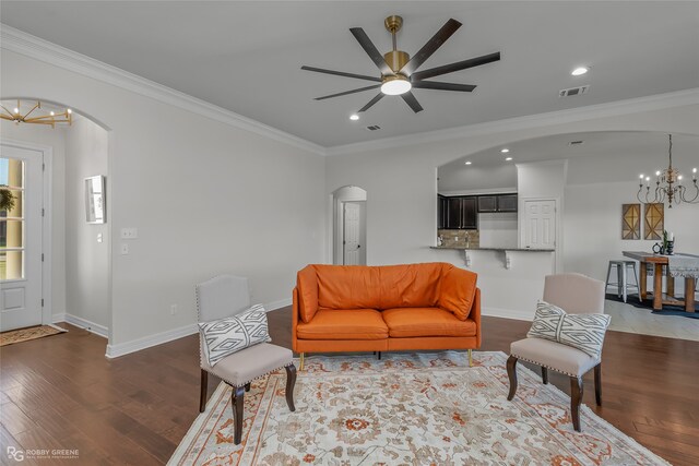 living room featuring ornamental molding, ceiling fan with notable chandelier, and dark wood-type flooring