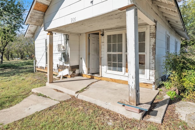 doorway to property with a lawn and covered porch