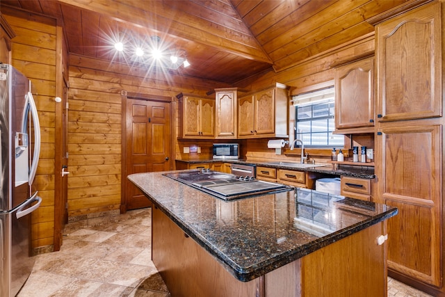 kitchen featuring wood walls, sink, a kitchen island, and appliances with stainless steel finishes