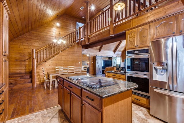 kitchen featuring wood ceiling, appliances with stainless steel finishes, dark stone countertops, wooden walls, and a center island