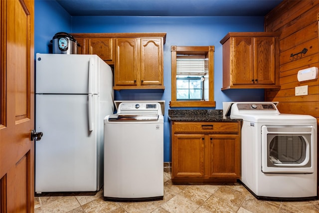 washroom with washer and clothes dryer and wood walls