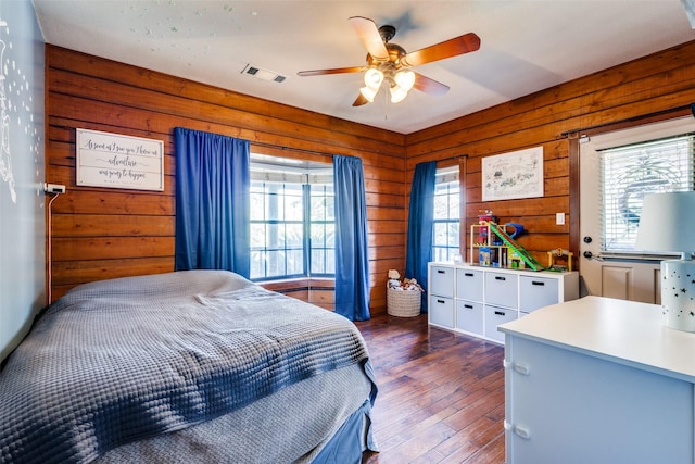 bedroom featuring dark wood-type flooring, ceiling fan, and wood walls