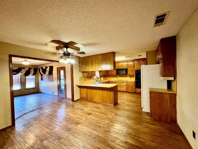 kitchen featuring kitchen peninsula, light wood-type flooring, a textured ceiling, ceiling fan, and black appliances