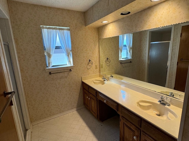 bathroom featuring tile patterned flooring, vanity, a shower with door, and a textured ceiling