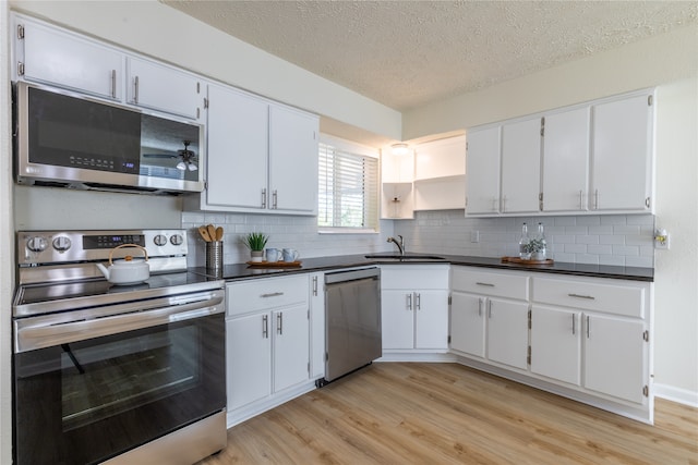 kitchen featuring sink, light wood-type flooring, a textured ceiling, appliances with stainless steel finishes, and white cabinetry