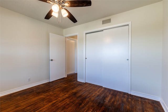 unfurnished bedroom featuring ceiling fan, a closet, and dark wood-type flooring