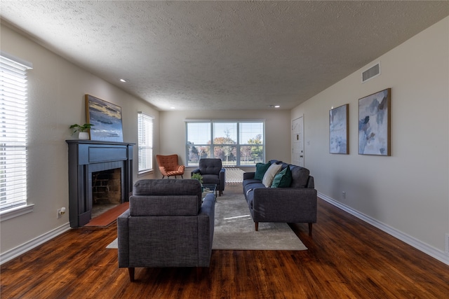 living room featuring a fireplace, dark hardwood / wood-style flooring, and a textured ceiling