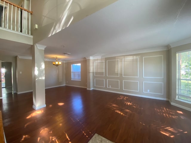 unfurnished living room featuring dark hardwood / wood-style flooring, a chandelier, and ornamental molding