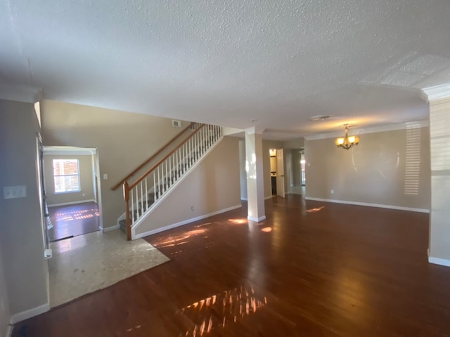 unfurnished living room featuring crown molding, dark hardwood / wood-style flooring, a chandelier, and a textured ceiling