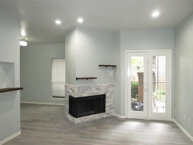 unfurnished living room featuring a stone fireplace and wood-type flooring