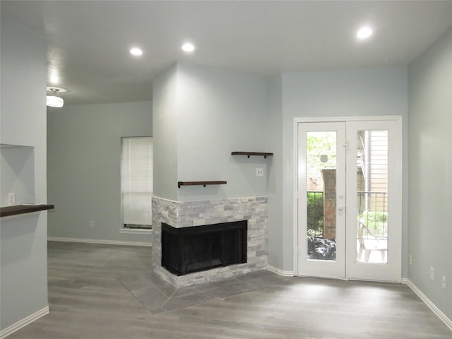 4715 N Galloway Ave Unit 104, Mesquite, TX 75150 - unfurnished living room featuring a stone fireplace, wood finished floors, recessed lighting, baseboards, and french doors