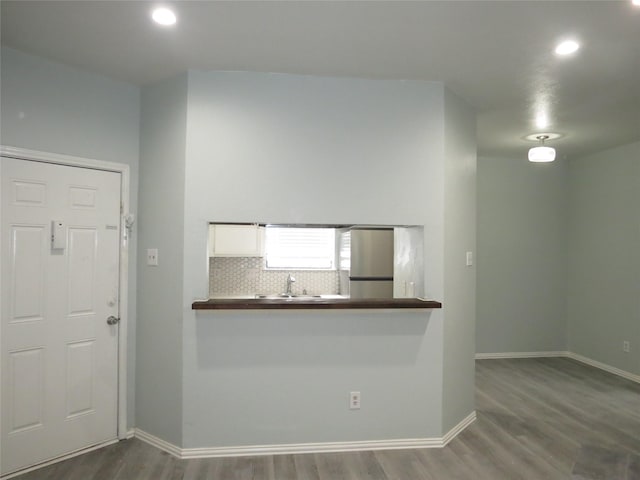 kitchen featuring backsplash, sink, hardwood / wood-style flooring, white cabinetry, and stainless steel refrigerator